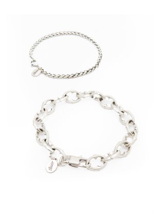 Brățările din lanțuri de argint sunt expuse: una cu un design împletit și o brățară mai mică cu zale, având un închizător și o etichetă.