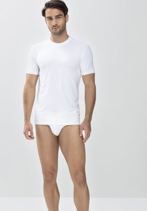 Weißes kurzärmeliges T-Shirt aus glattem Stoff, mit Rundhalsausschnitt und normaler Passform. Kombiniert mit weißen Unterhosen.