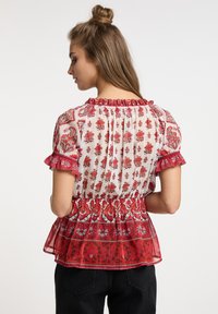 Rote Bluse mit floralem Druck, gerafftem Kragen, kurzen Ärmeln und Rüschendetails. Leichter Stoff mit Peplum-Design und strukturierten Details.