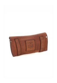 Custodia in pelle marrone con chiusura a scatto, forma arrotondata, etichetta rettangolare e due cinghie cucite. Texture liscia e dettagli hardware minimi.