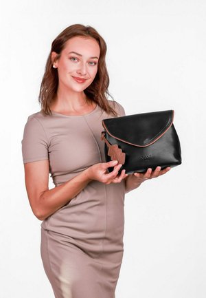 Černá kožená taška s klopou a hnědým cikcak detailem, s hladkým povrchem a pevným tvarem, držena osobou.