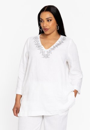 Witte linnen blouse met een V-hals en 3/4 mouwen, afgewerkt met zwarte decoratieve borduursels langs de halslijn. Ontspannen pasvorm met zijzakken.