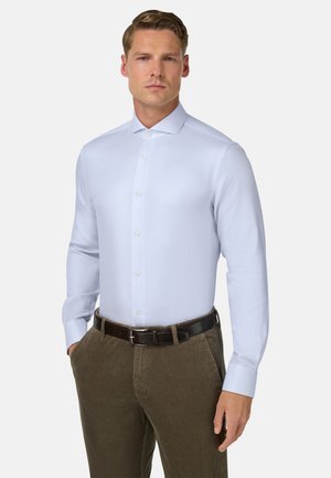 Lichtblauw, lang mouw shirt met een puntige kraag en knoopsluiting, gecombineerd met brown corduroy broek en een zwarte riem. Gladde textuur.