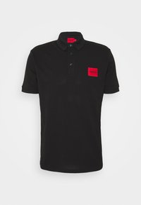 Polo noir à manches courtes avec trois boutons et un patch rectangulaire rouge portant l'inscription "HUGO" sur la poitrine gauche.