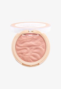 Polvere blush in una compatta rotonda con una tonalità pesca chiara. Design a onde testurizzate sulla superficie, coperchio trasparente e confezione beige.
