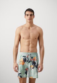 Pantaloni de baie pentru bărbați dintr-un material verde deschis cu un model floral în nuanțe de portocaliu și negru. Au o talie elastică și șnur.