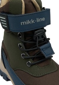 Dětská hnědo-zelená bota s modrým páskem, vybavená strukturovanými materiály, černými tkaničkami a kovovými očka pro odolnost.