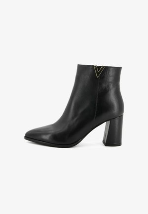 Stivaletto in pelle nera con punta affilata, tacco a blocco e dettaglio oro a forma di "V" vicino al bordo superiore, su sfondo bianco.