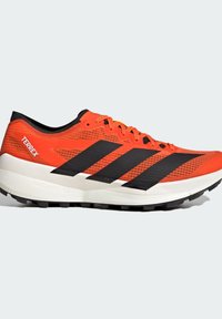 Lys orange Adidas Terrex trailsko til løb med sorte striber, hvid polstret sål og robust sort ydersål for godt greb.