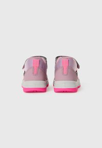 Ein Paar rosa und lila Kinderschuhe mit leuchtend rosa Sohlen, von hinten auf einem weißen Hintergrund gezeigt.