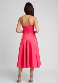 Różowa sukienka bez ramiączek z gładkiego materiału, dopasowana w talii z rozkloszowanym, do kolan długością spódnicą. Posiada zamek błyskawiczny z tyłu.