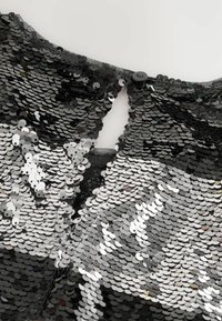 Top nero di paillettes con superficie testurizzata, caratterizzato da paillettes alternate argento e nere, e chiusura con bottone sul retro.