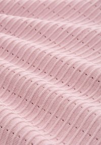 Różowy dzianinowy materiał z falistym wzorem, ozdobiony małymi otworami na całej powierzchni, prezentujący fakturowaną powierzchnię i miękki wygląd.