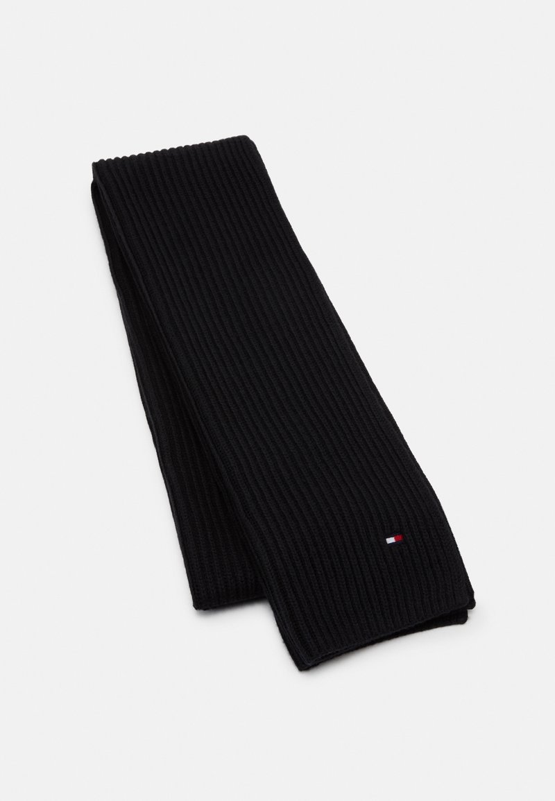 Écharpe noire à côtes en tissu tricoté, avec un petit logo en rouge, blanc et bleu. Forme longue et rectangulaire, avec une surface texturée.