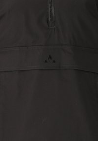 Svart halvdraget pullover tillverkad av ett mjukt och lätt tyg. Har en sydd söm och en liten triangulär logotyp nära fållen.
