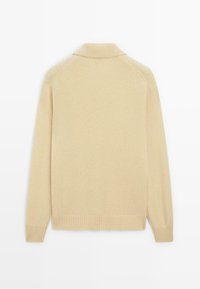 Maglione lavorato a maglia beige con colletto, polsini e orlo a costine. Presenta una texture liscia con cuciture sottili lungo le spalle.