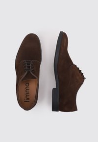 Pareja de zapatos de vestir para hombre en ante marrón oscuro con suelas y cordones negros, un zapato mostrando la vista superior y el otro la vista lateral.