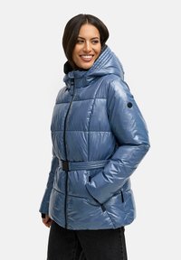 Blå pufferjakke med en skinnende finish, quiltet design, justerbar hætte og bæltestrop i taljen. Har sorte accenter og lynlåslommer.