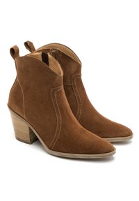 Brązowe zamszowe botki za kostkę z ostrym noskiem, z małym, zakręconym obcasem i białymi niciami, a także pętelkami po obu stronach.
