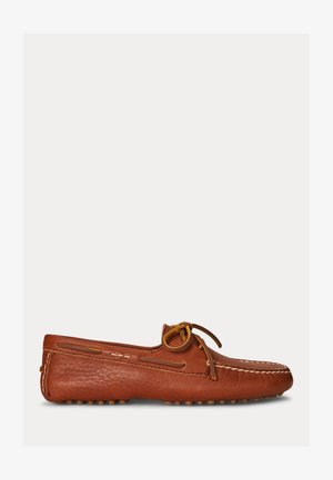 Brūns ādas mokasīnu loaferis ar dzeltenu mežģīņu loku un šūtu dekorāciju, attēlots sānskatā uz vienkārša fona.