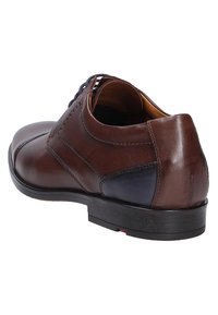 Brown leather shoe featuring a rounded toe, smooth texture, a contrasting blue panel, and a black rubber sole. Laces are at the front.
