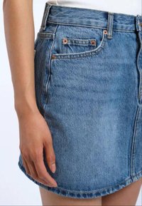 Gonna di jeans in blu chiaro con un design dritto. Presenta tasche frontali, cuciture a vista e un orlo che curva leggermente.