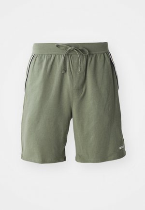 Shorts en coton verts avec une taille élastique et un cordon de serrage. Caractéristiques de rayures latérales et d'un logo sur l'ourlet inférieur. Texture lisse.