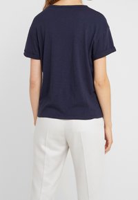 Mørkeblå kortærmet t-shirt med opsmøgede ærmer, lavet af blødt stof, med en afslappet pasform og et enkelt rundhalset design.