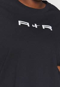 Camiseta de algodón negra con cuello redondo y texto en blanco audaz "A I R" con el logo de Nike. Diseño simple con una textura suave.