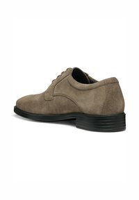 Zapato de vestir de ante marrón con puntera redondeada, diseño de cordones y suela de goma negra con ranuras horizontales para tracción.