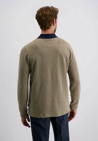 Beige strukturiertes Langarmhemd mit marineblauem Kragen und einem dezenten Muster. Die Rückansicht zeigt eine lockere Passform und einen abgerundeten Saum.