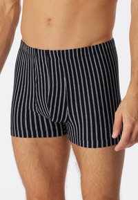 Boxer shorts a strisce nere realizzati in tessuto morbido, con sottili strisce bianche verticali, un design aderente e una cintura elastica.
