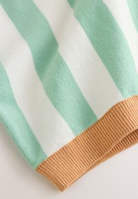 Tissu en maille douce avec de larges rayures verticales vert menthe et blanc, se terminant par un poignet côtelé marron clair.