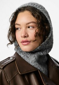 Cappuccio grigio lavorato a maglia con texture a coste e finitura morbida, abbinato a una giacca di pelle marrone scuro con bottoni a pressione.