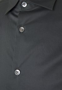 Mörkgrå skjorta med krage som har en slät textur, femknappsfront med glänsande grå knappar och diskret sömnadsdetalj längs kragen.