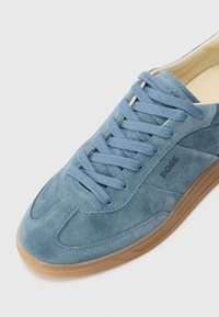 Sneaker in suede blu, con punta rotonda, lacci coordinati e suola in gomma. Presenta un logo impresso di lato e dettagli di cucitura.