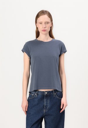 T-shirt grigio scuro a maniche corte con scollo rotondo, vestibilità comoda e maniche arrotolate, abbinato a jeans blu a vita alta.