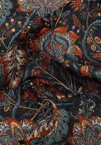 Tela con un patrón floral que presenta un fondo oscuro con flores rojas, naranjas y azules. La textura del tejido realza la profundidad y el detalle.