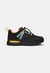 Basket basse noire avec détail jaune au talon, passants verts, doublure intérieure orange et lacets élastiques à bouton-pression sur fond blanc.