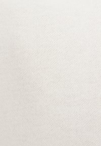 Tessuto strutturato di colore beige chiaro con un motivo sottile di piccoli puntini; il materiale sembra tessuto e leggermente elastico.