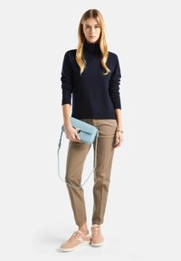 Granatowy sweter, beżowe spodnie, różowe sneakersy i jasnoniebieska torebka na ramię. Posiada kołnierz typu golf i gładką fakturę z wyraźnie zarysowanym krojem.