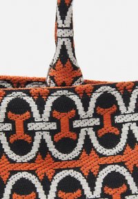 Geweven draagtas met een kleurrijk geometrisch patroon in oranje, zwart en wit, van stevig stof en met twee handvatten.