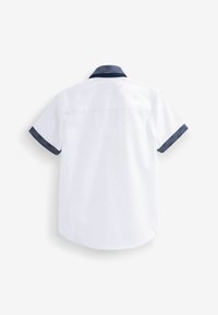 Chemise blanche à manches courtes avec col et poignets bleu marine à motifs, vue de dos sur un fond uni.