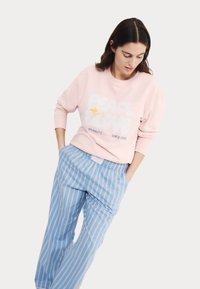 Ljust rosa sweatshirt med grafiken "PEACE & LOVE", parat med blå och vita randiga byxor. Mjuk tyg och avslappnad passform.