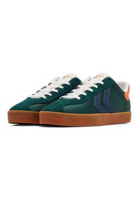Grüne Wildledersneaker mit weißen Schnürsenkeln, die dunkelblaue Streifen und einen orangefarbenen Akzent an der Ferse haben. Gummisohle mit strukturiertem Finish.