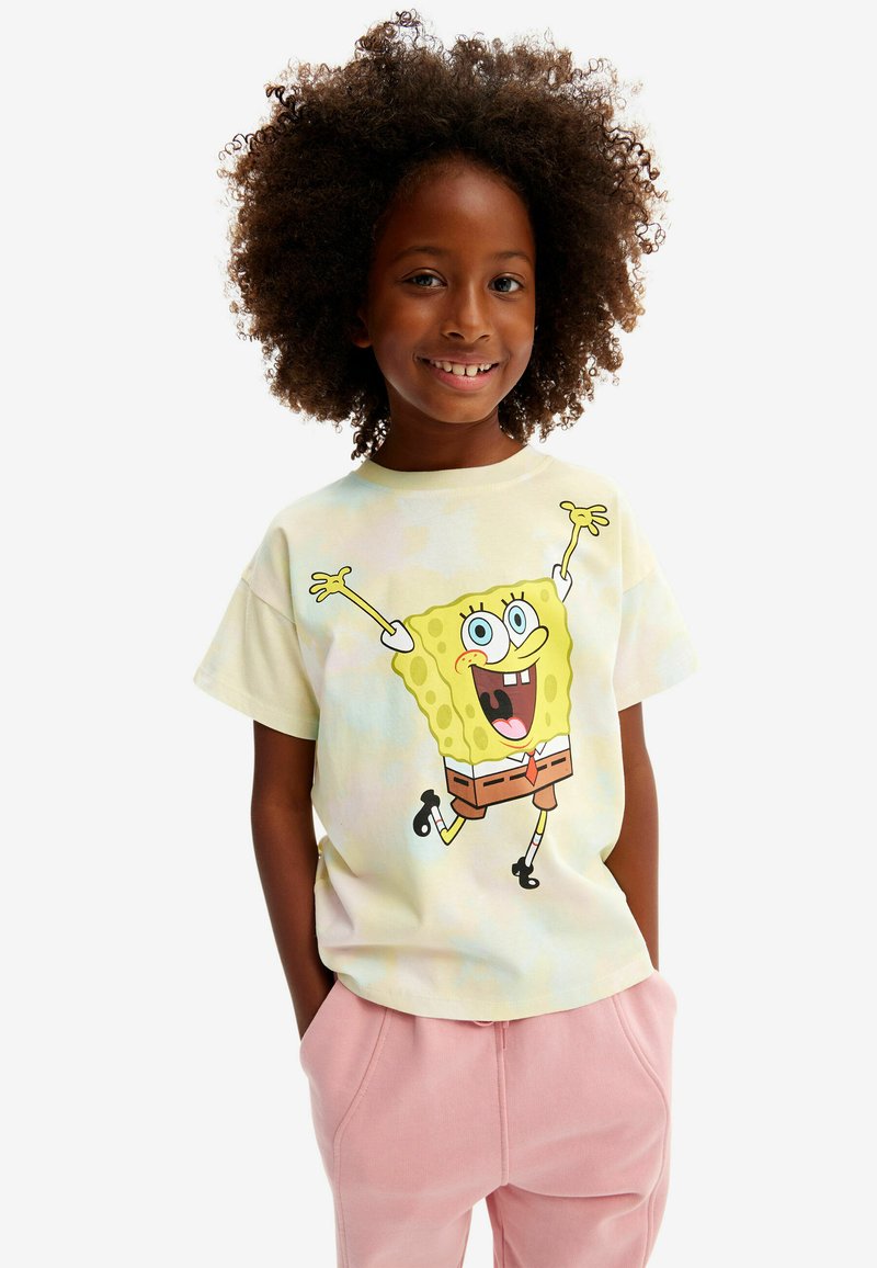 T-shirt tie-dye pastel clair avec un graphique de SpongeBob SquarePants jaune vif, associé à un pantalon de jogging rose clair.