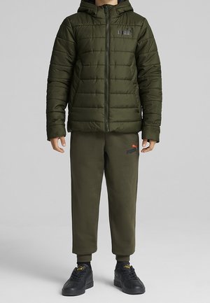 Veste matelassée vert olive avec capuche, design matelassé et fermeture éclair à l'avant. Associée à un pantalon de survêtement assorti et des baskets noires.