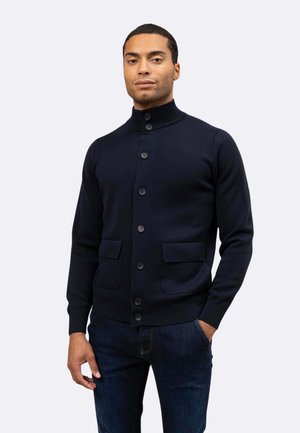 Cardigan blu navy con colletto alto, chiusura a bottoni e due tasche frontali. Realizzato in tessuto testurizzato, design aderente e polsini a coste.