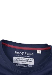 Marineblå t-shirt med krave i maroon kant. Etiket siger "Band of Rascals" og indikerer 100% økologisk bomuld samt overensstemmelse med tekstilstandarder.