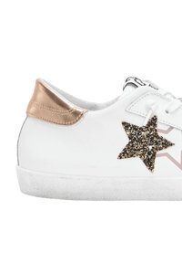 Sneaker bianca in pelle con dettaglio di stelle laminato oro e nero, accentuazione del tallone metallico dorato e suola in gomma texturizzata bianca.